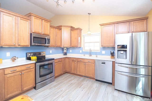 kitchen with lofted ceiling, light countertops, a sink, appliances with stainless steel finishes, and decorative light fixtures