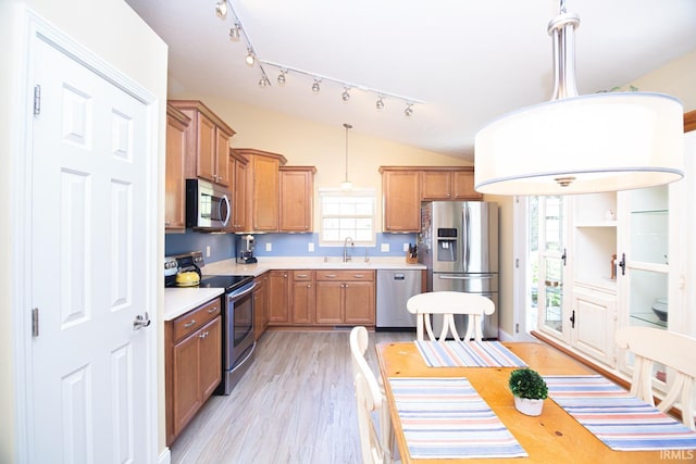 kitchen featuring light wood-type flooring, light countertops, brown cabinets, a sink, and appliances with stainless steel finishes