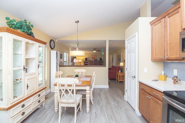 dining area featuring baseboards, ceiling fan, light wood-style flooring, and lofted ceiling
