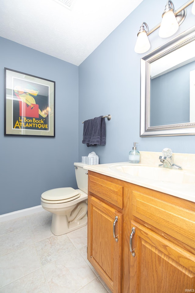 bathroom featuring vanity, baseboards, toilet, and tile patterned flooring