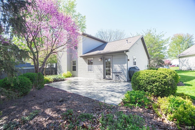 back of property with roof with shingles, fence, and a patio area