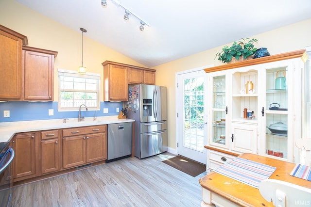 kitchen featuring brown cabinets, stainless steel appliances, vaulted ceiling, and light countertops