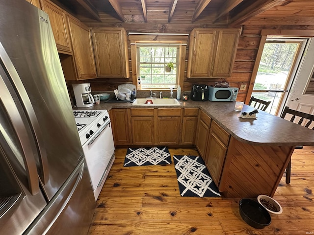 2340 W County Rd 550 S, Paoli, IN 47454 - kitchen with freestanding refrigerator, wood walls, a peninsula, white range with gas stovetop, and a sink