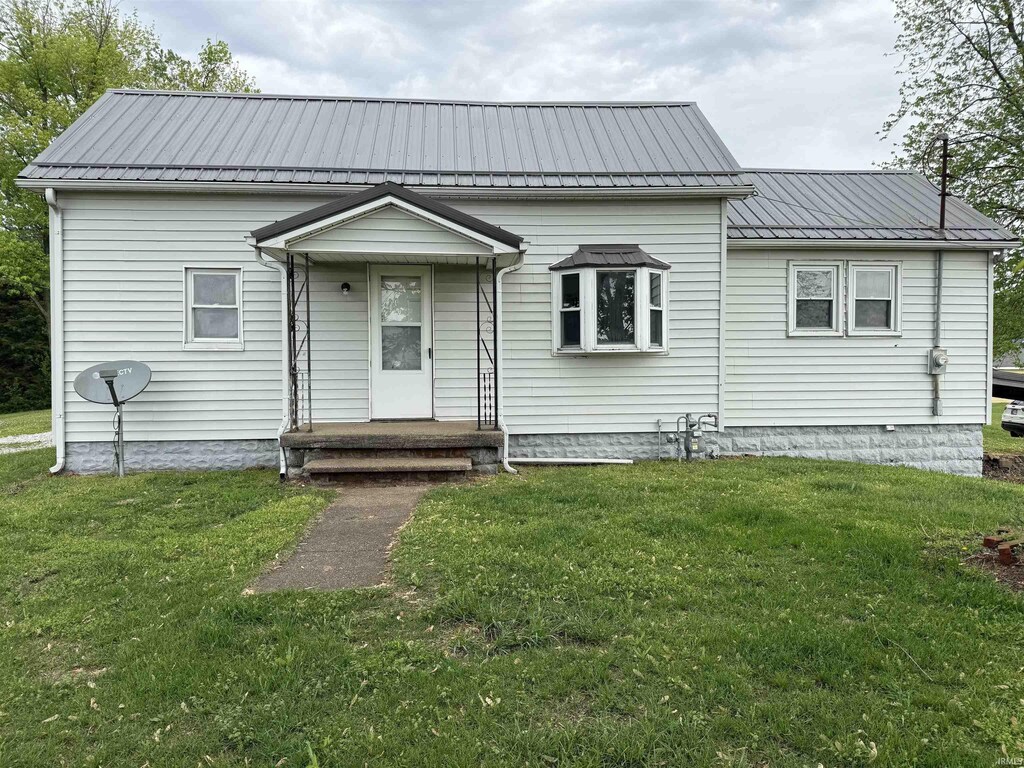 view of front of property with metal roof and a front lawn