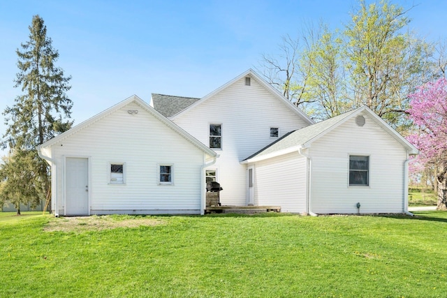 back of house with a lawn and a shingled roof