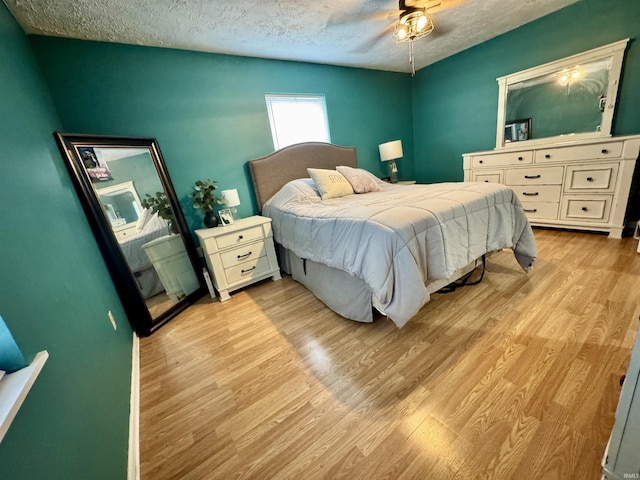 bedroom featuring a textured ceiling, light wood finished floors, and ceiling fan