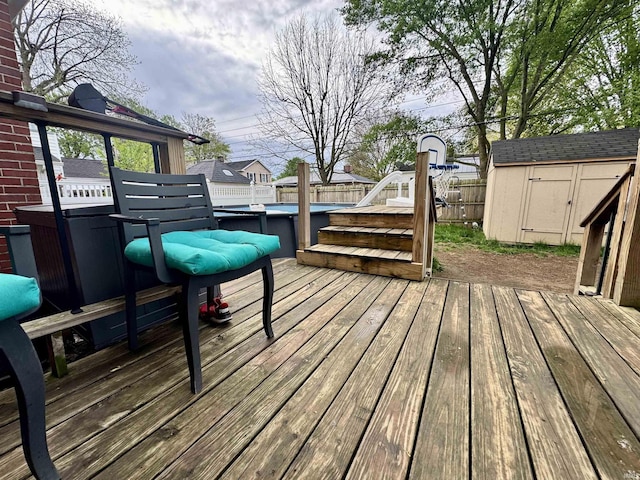 wooden terrace featuring fence, a fenced in pool, an outbuilding, and a shed