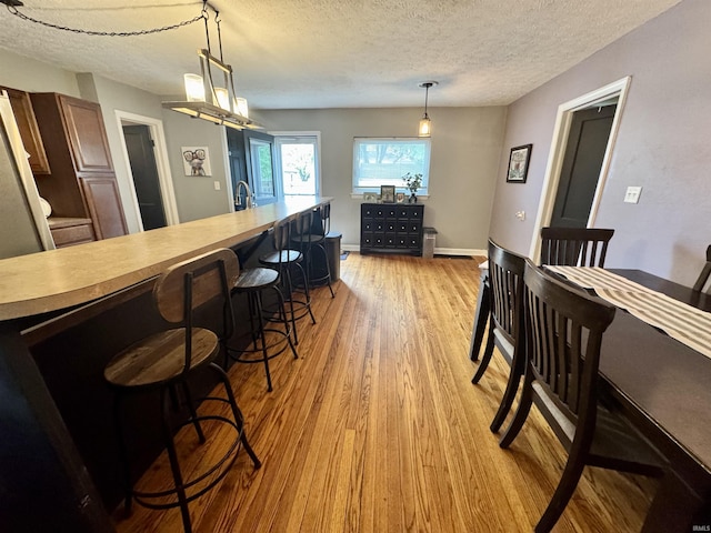 dining space featuring light wood-style floors and a textured ceiling