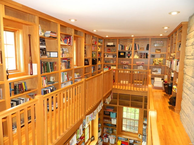living area with recessed lighting, wood finished floors, a wealth of natural light, and bookshelves