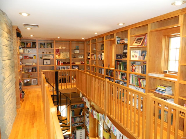 interior space featuring recessed lighting, visible vents, wood finished floors, and an upstairs landing