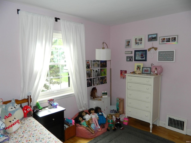 bedroom featuring wood finished floors and visible vents