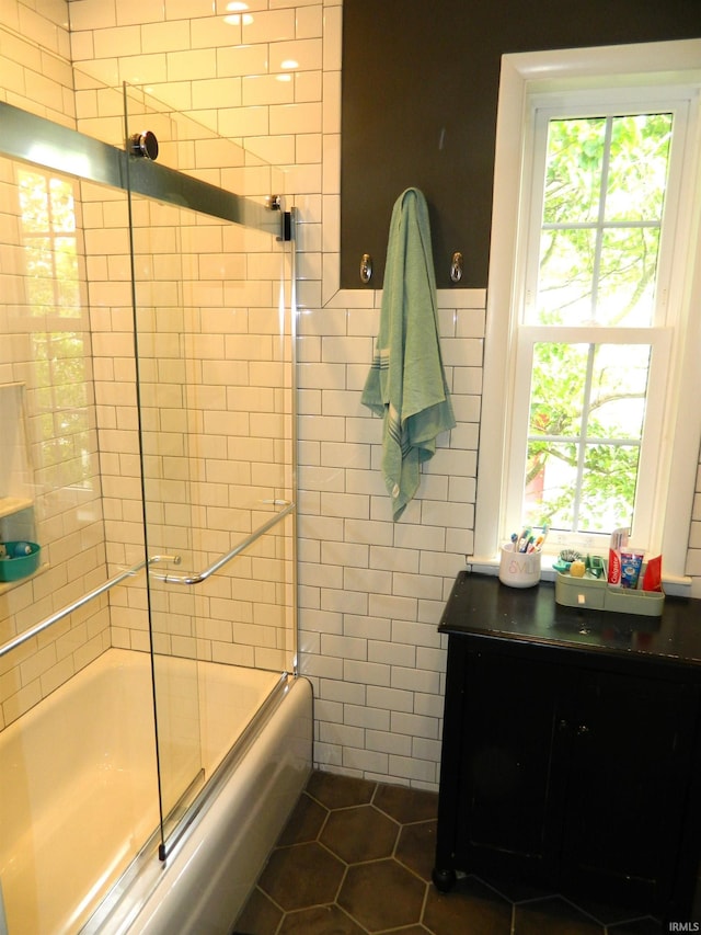 bathroom featuring tile walls, enclosed tub / shower combo, tile patterned floors, and a wealth of natural light
