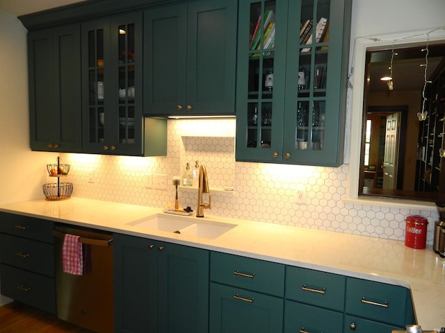 kitchen featuring glass insert cabinets, light countertops, tasteful backsplash, a sink, and dishwasher
