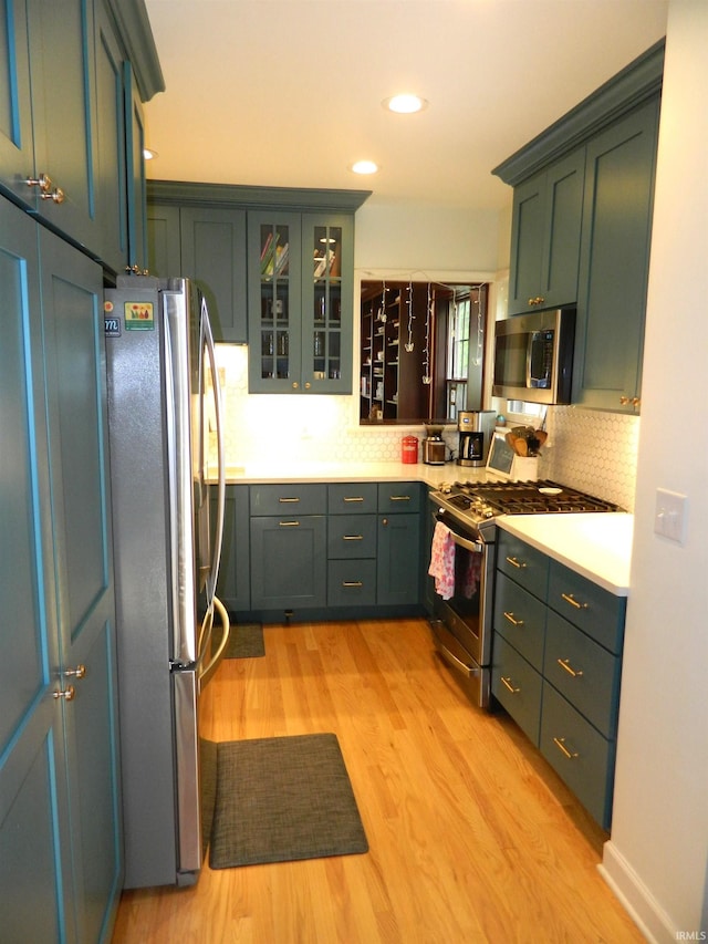 kitchen featuring light countertops, light wood finished floors, backsplash, and stainless steel appliances