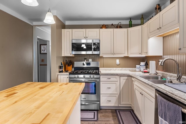 kitchen featuring a sink, stainless steel appliances, butcher block counters, and white cabinetry