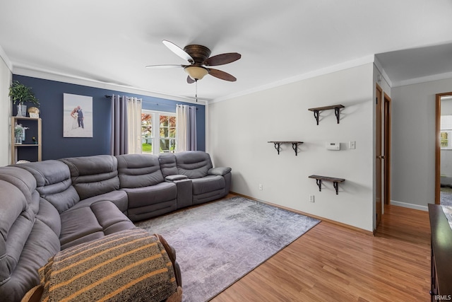 living area featuring baseboards, ceiling fan, ornamental molding, and light wood-type flooring