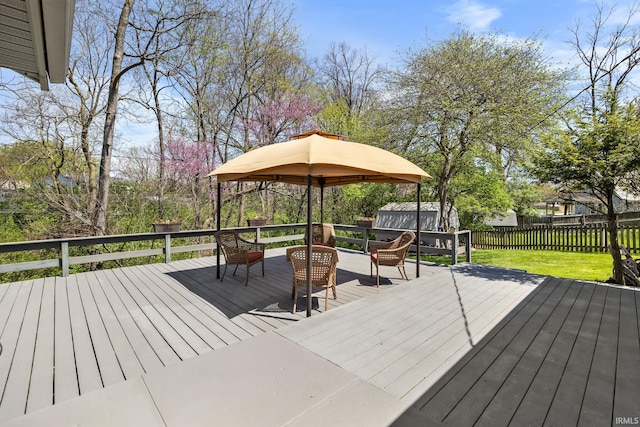 wooden terrace with fence, a storage unit, an outdoor structure, and a yard