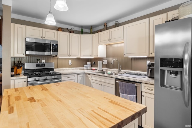 kitchen with a sink, appliances with stainless steel finishes, wooden counters, and white cabinetry