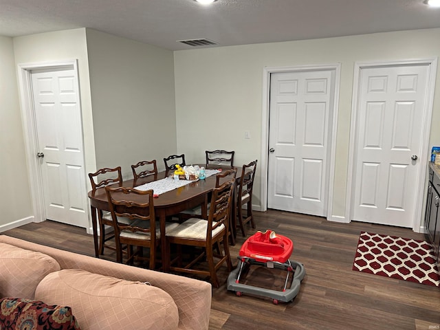 dining area with dark wood-type flooring, baseboards, and visible vents