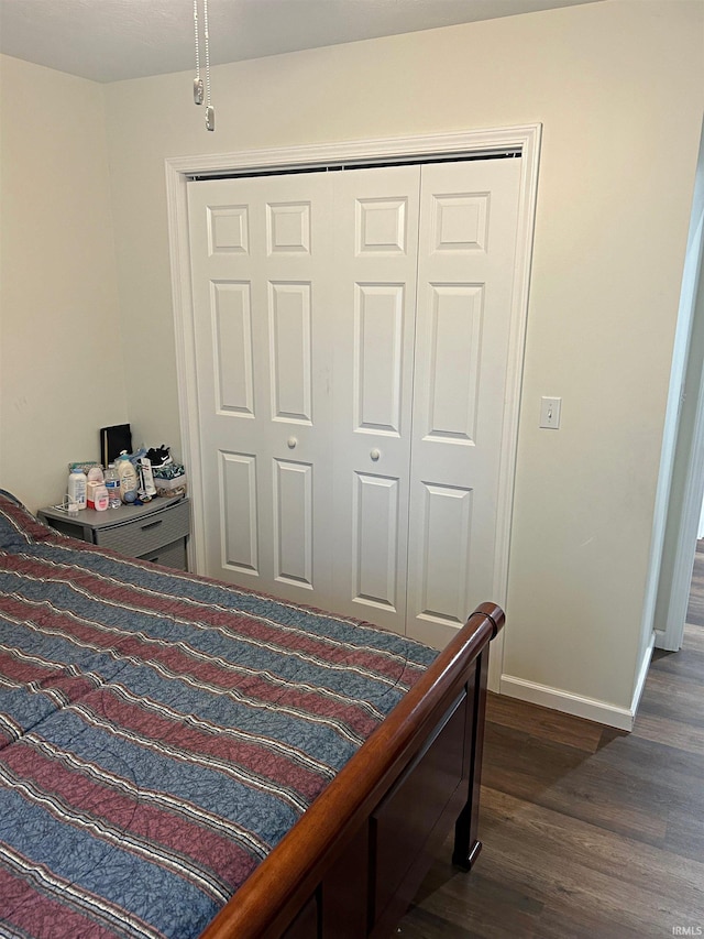 bedroom featuring baseboards, dark wood-style floors, and a closet