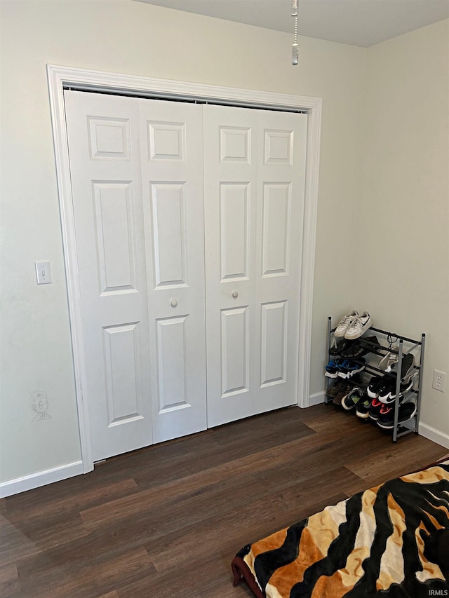 bedroom featuring baseboards, dark wood finished floors, and a closet