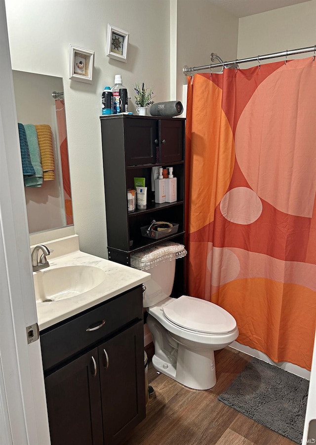 bathroom with vanity, wood finished floors, toilet, and curtained shower