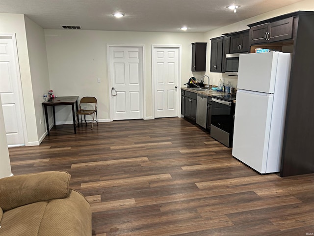 kitchen featuring dark wood-style flooring, stainless steel appliances, visible vents, and a sink