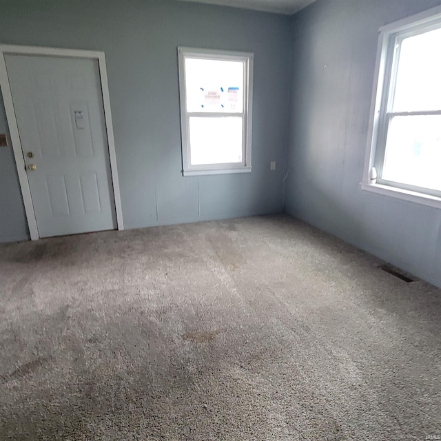 carpeted empty room featuring visible vents