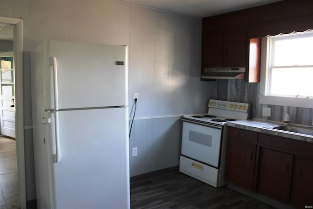 kitchen featuring dark brown cabinets, a sink, dark wood-style floors, under cabinet range hood, and white appliances
