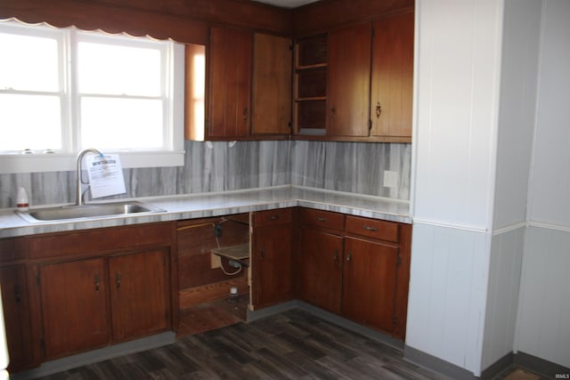 kitchen featuring brown cabinets, open shelves, a sink, light countertops, and dark wood finished floors