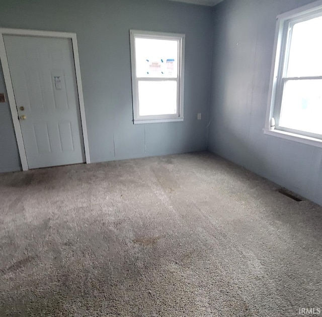 spare room featuring visible vents, carpet flooring, and a healthy amount of sunlight