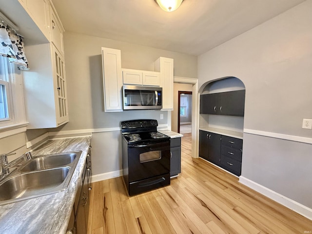 kitchen with white cabinets, electric range, a sink, light wood-style floors, and stainless steel microwave
