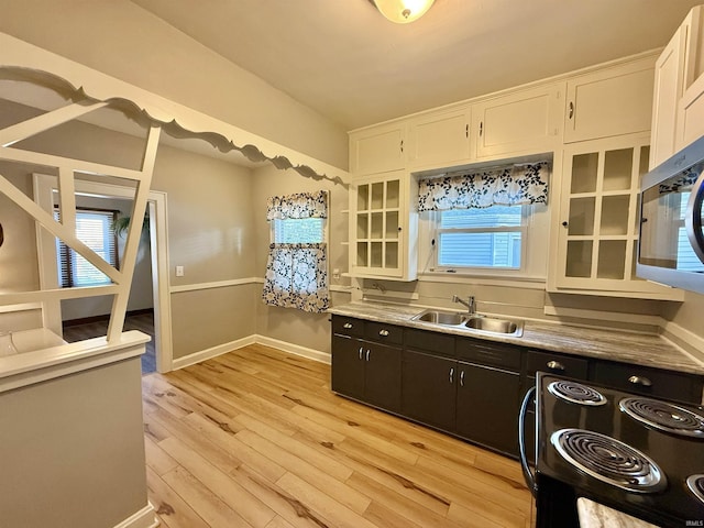 kitchen with a sink, light wood finished floors, white cabinetry, black / electric stove, and glass insert cabinets