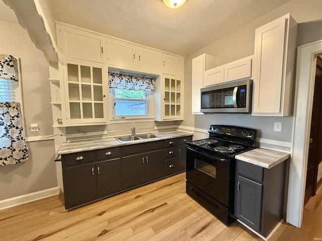 kitchen with white cabinetry, stainless steel microwave, black electric range, and a sink
