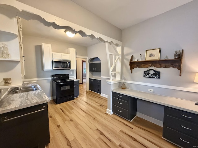 kitchen featuring light wood-style floors, a sink, light countertops, black appliances, and dark cabinets
