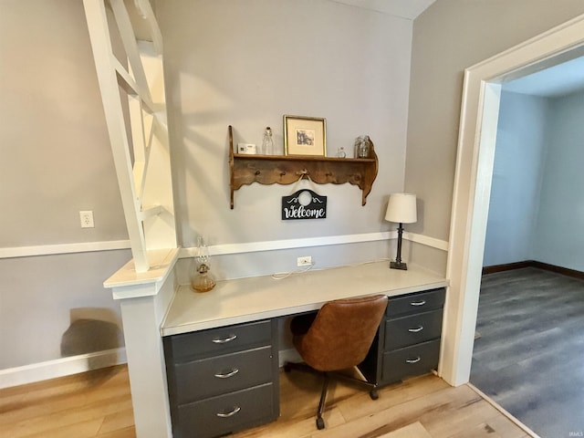 office with built in study area, baseboards, and light wood-style flooring