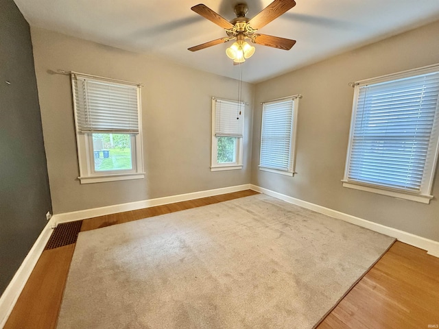 spare room with baseboards, ceiling fan, and wood finished floors