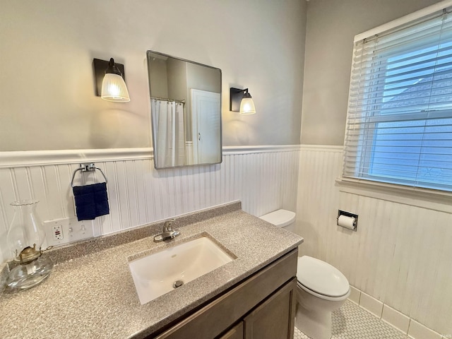 bathroom featuring vanity, tile patterned floors, wainscoting, and toilet
