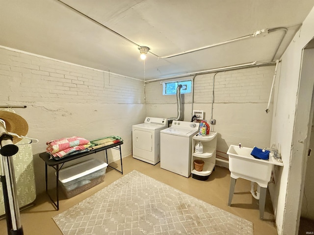 washroom featuring brick wall, washing machine and dryer, and laundry area