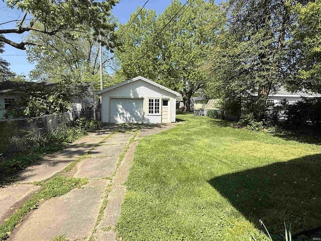 view of yard featuring a detached garage, fence, an outbuilding, and concrete driveway