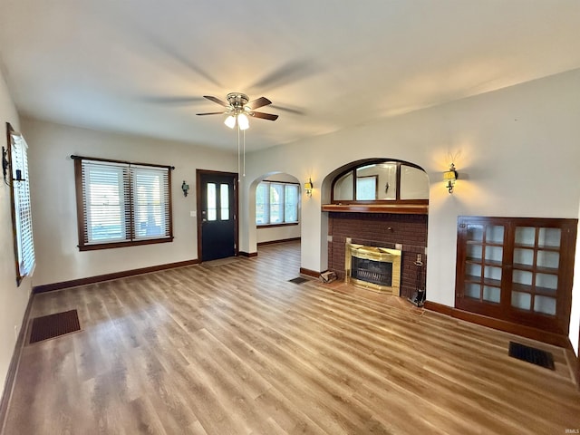 unfurnished living room featuring visible vents, baseboards, wood finished floors, and a fireplace