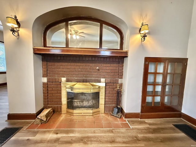 details featuring a brick fireplace, baseboards, visible vents, and wood finished floors