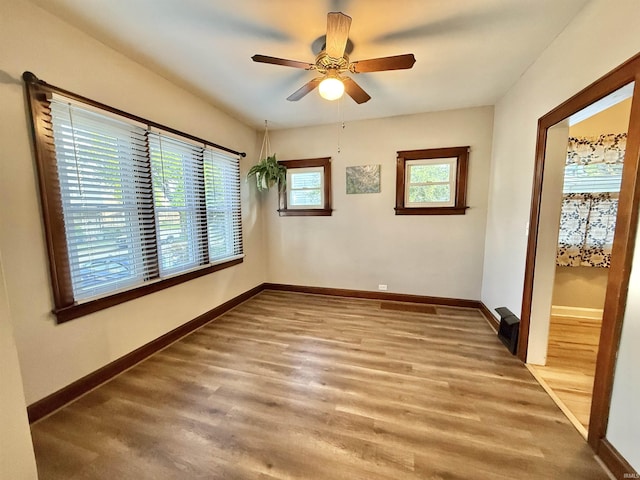 empty room with a ceiling fan, baseboards, and wood finished floors