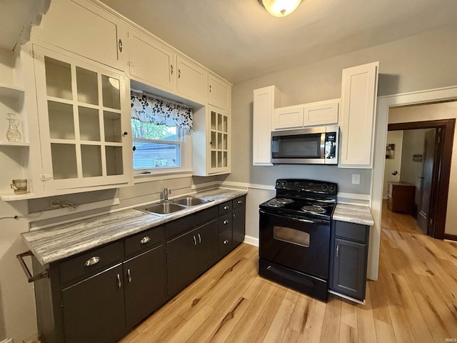 kitchen with black electric range oven, light wood-type flooring, a sink, white cabinets, and stainless steel microwave