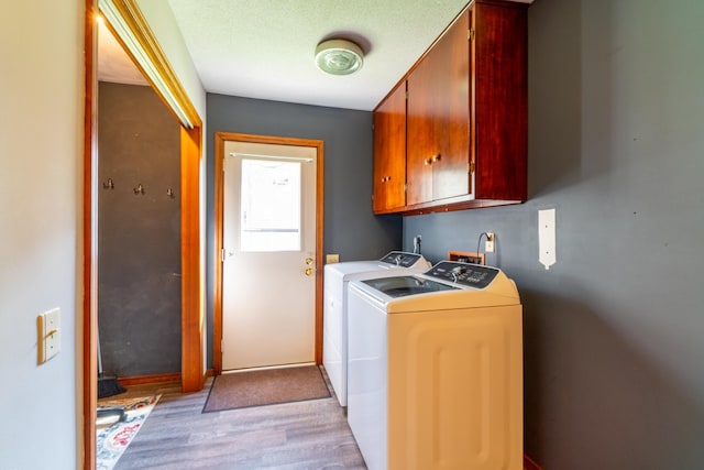 laundry area with light wood-style floors, baseboards, cabinet space, and washer and dryer