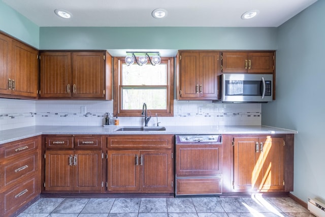 kitchen featuring a sink, light countertops, stainless steel microwave, and dishwasher