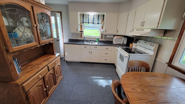 kitchen with dark countertops, white appliances, under cabinet range hood, white cabinets, and a sink