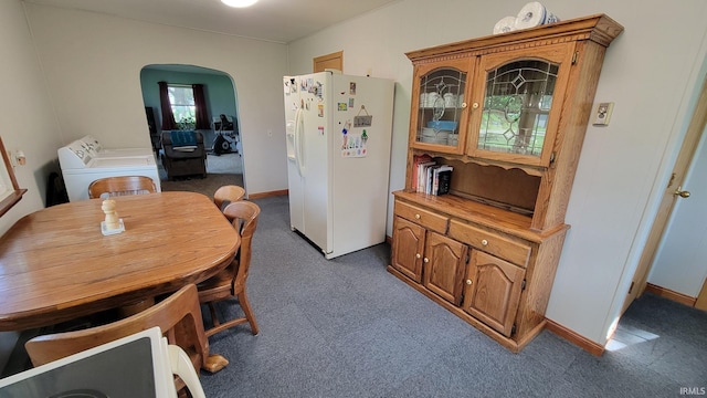dining space featuring baseboards, arched walkways, carpet, and washer and dryer