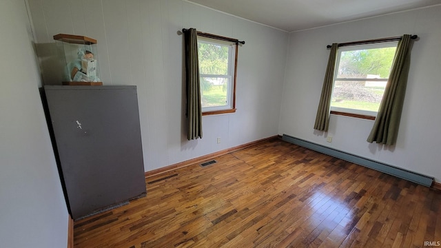 unfurnished room with ornamental molding, a wealth of natural light, hardwood / wood-style flooring, and a baseboard radiator