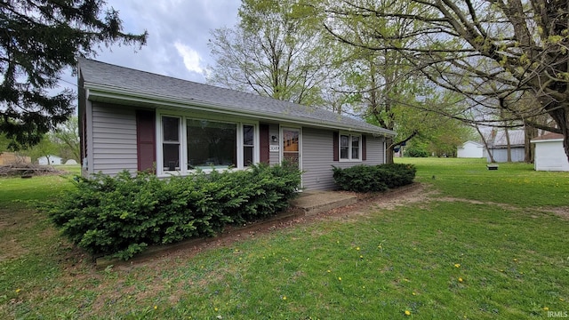 exterior space with a shingled roof and a front lawn